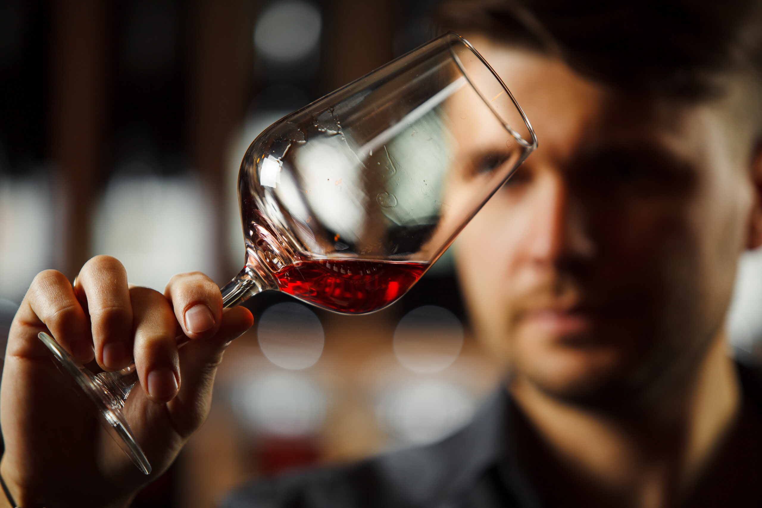 Bokal of red wine on background, male sommelier appreciating drink